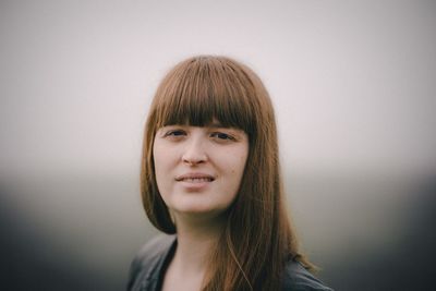 Portrait of smiling young woman against gray background