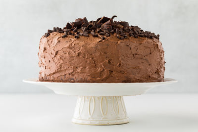 A whole triple layered low sugar chocolate cake on a pedestal stand.