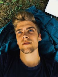 High angle view of handsome young man looking away while lying on land