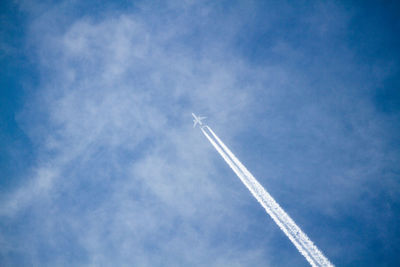 Low angle view of airplane flying against blue sky