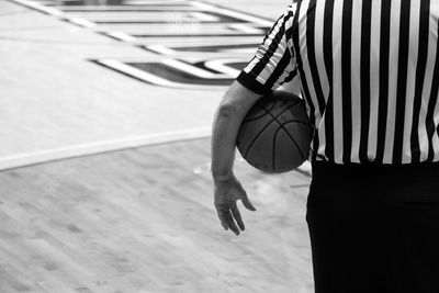 Rear view of man holding ball and standing on floor