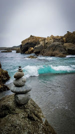 Rocks on sea shore against sky