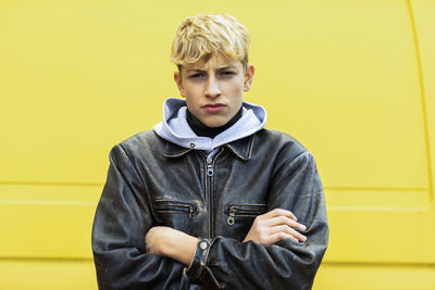 Portrait of young man standing against yellow wall