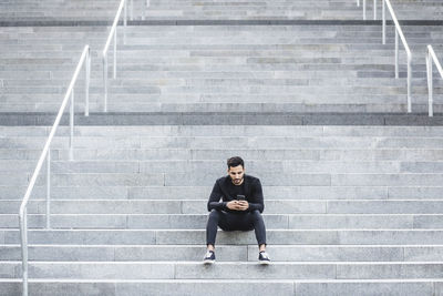 Young man using smart phone while sitting on staircase