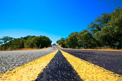 Road amidst trees against clear sky