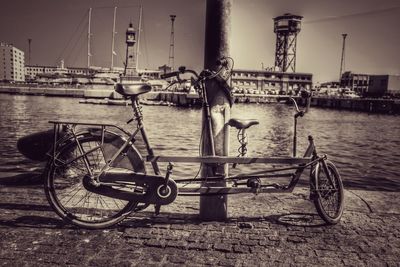 Bicycles on bridge over sea against sky in city