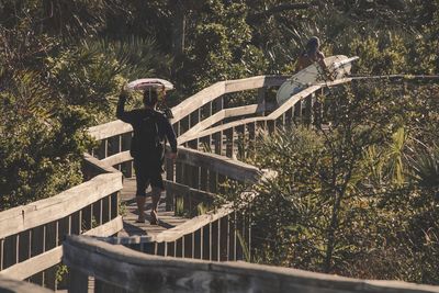 Rear view of man standing by railing against trees