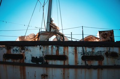 Low angle view of abandoned ship against clear blue sky