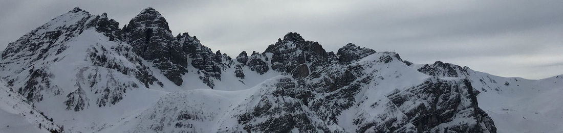 Panoramic view of snow covered mountains against sky