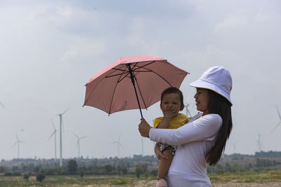 A young mother and her lovely little daughter are at a windmill field.