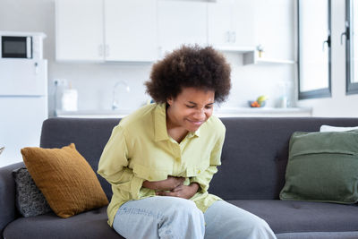 Young woman using laptop while sitting on sofa at home