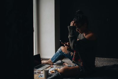 Woman using mobile phone while siting at home