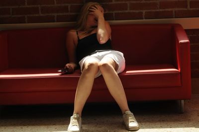 Full length of woman sitting against wall at home