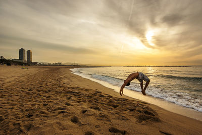 Man on beach against sky during sunset