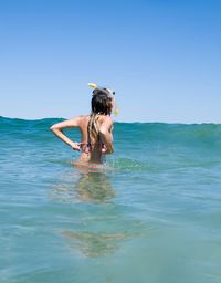 Woman snorkeling in sea against clear blue sky