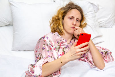 Young woman using mobile phone on bed at home