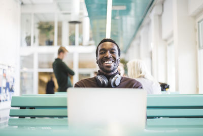 Portrait of smiling male student sitting in cafeteria at university