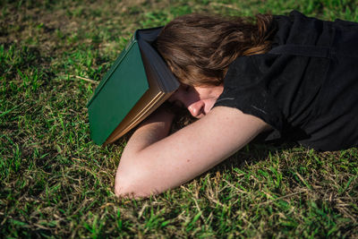 High angle view of woman with book lying on field