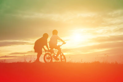 Silhouette man riding bicycle against sky during sunset