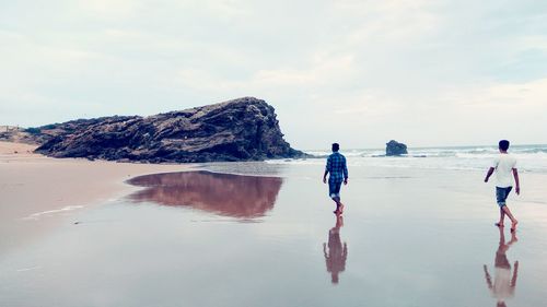 People standing on beach against sky