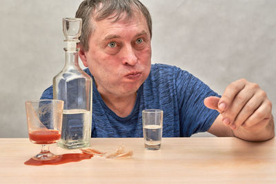 Portrait of man holding bottle on table