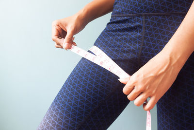 Midsection of woman holding paper while standing against white background