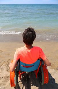 Rear view of man sitting on beach