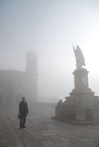 Man standing on historic square in a misty day