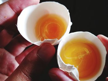 Close-up of hand holding egg yolks against black background