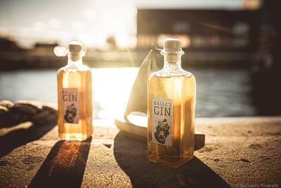 Close-up of bottle on table at beach during sunset