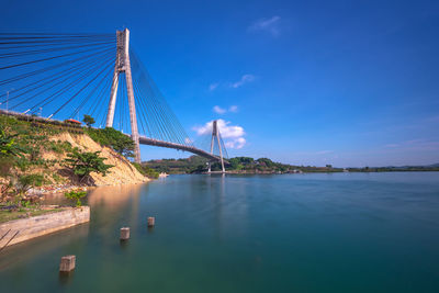 View of bridge over bay against blue sky