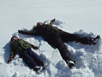 Full length of woman sitting on snow covered field