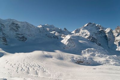 Scenic view of snowcapped mountains against blue sky