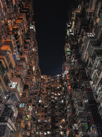 Low angle view of illuminated buildings against sky at night