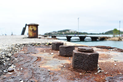 Close-up of rusty metal on beach against sky