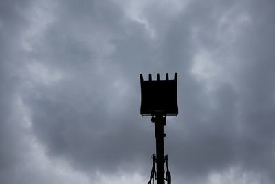 Low angle view of bird perching on pole against sky