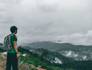 Rear view of man standing against mountain and sky