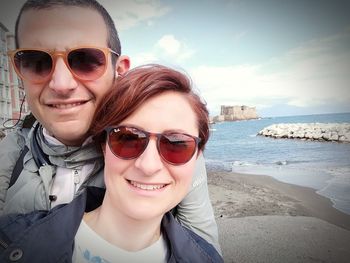 Smiling couple wearing sunglasses at beach