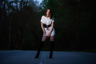 Portrait of young woman standing against trees