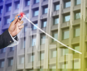 Digital composite image of businessman drawing graph against building