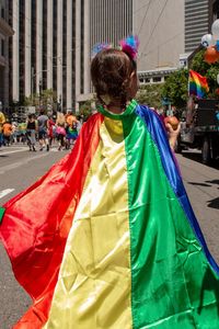 Girl wearing rainbow cape on street