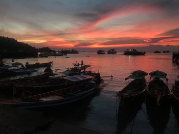 Boats moored in sea at sunset