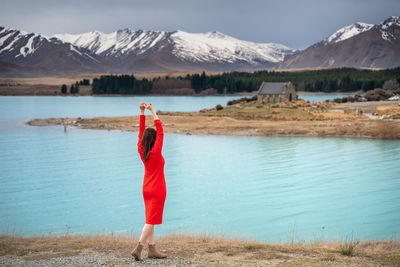 Asian female tourist pose at turquoise color lake tekapo with snowcapped mountain at the background