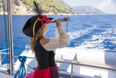 Woman looking through binoculars in boat on sea