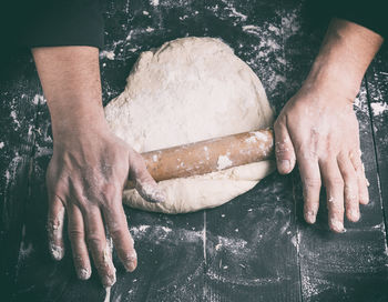 Close-up of man rolling dough at kitchen counter