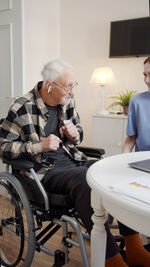 Side view of man using mobile phone while sitting on table