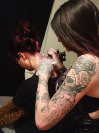 Artist doing tattoo on neck of customer