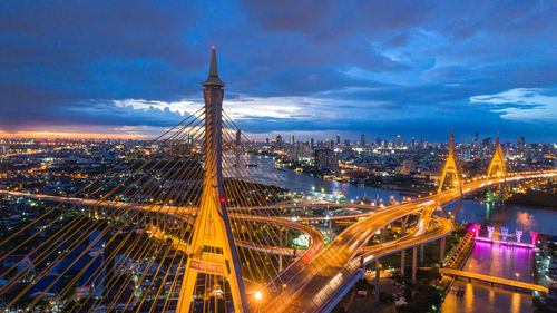 Aerial view of illuminated bridge and buildings against sky at night