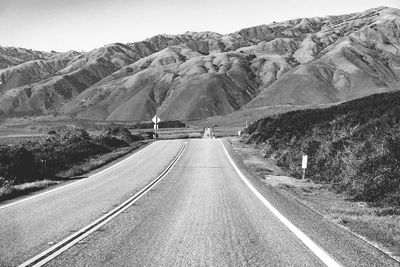 Road leading towards mountains against sky