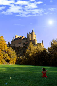 Rear view of woman sitting in park against sky